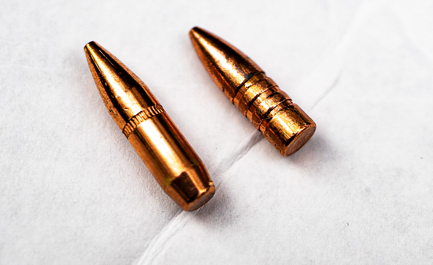 A boat tail bullet next to a bullet with flat base A boat tail bullet side by side with a flat base bullet