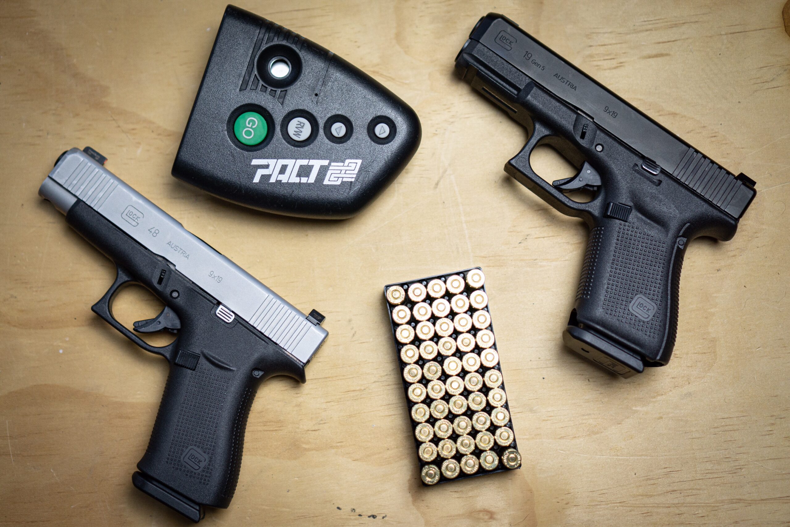 Glock 48 And Glock 19 with shot timer and ammo on a table